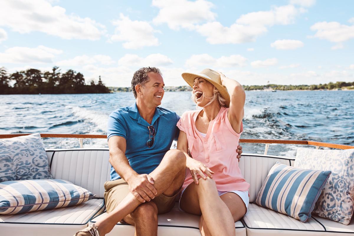 Couple laughing while enjoying time on their boat on a sunny day.